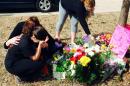 CORRECTS LAST NAME OF VICTIM'S MOTHER TO BARFIELD INSTEAD OF OWENS - Stacey Barfield, mother of Hailey Owens, foreground left, is consoled by Sara Wells, as family member Teri Nord, right, arranges flowers left by well wishers Thursday, Feb. 20, 2014 near the site where the 10-year-old girl was abducted just blocks from her Springfield, Mo., home. Prosecutors have charged Craig Michael Wood with first-degree murder, kidnapping and armed criminal action in their girls death. Prosecutors says the fourth-grader's body was found stuffed in two trash bags inside plastic storage containers in the basement of Wood's Springfield home. She had been shot in the head. (AP Photo/Alan Scher Zagier)