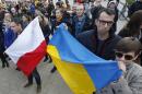 In this photo taken on Sunday, Feb. 23, 2014, people holding a Poland flag, left, and a Ukraine flag listen to speakers during a demonstration in Warsaw, Poland showing their support for protesters in Ukraine. Broken promises of help from the West. A tragic history of Russian invasion that goes back centuries. A painful awareness that conflicts in this volatile region are contagious. These are the factors that make nations across Eastern Europe watch events in Ukraine. Some countries like Poland, which shares a border with both Ukraine and Russia, are already starting to take precautionary measures. Polish Prime Minister Donald Tusk has warned that instability in Ukraine may be prolonged and lead Warsaw to upgrade its weapons. (AP Photo/Czarek Sokolowski)