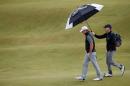 US golfer Jordan Spieth (L) is protected from the rain under an umbrella during a practice round on The Old Course at St Andrews in Scotland, on July 15, 2015, ahead of The 2015 Open Golf Championship