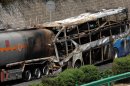 In this photo released by China's Xinhua News Agency, the burnt wreckage of a double-decker sleeper bus and a tanker loaded with highly-flammable methanol sit on a highway in Yan'an City, northwest China's Shaanxi province on Sunday, Aug. 26, 2012. The 39-seat bus rammed into the tanker early Sunday, causing both vehicles to burst into flames and killing 36 people, state media said. (AP Photo/Xinhua, Li Yibo) NO SALES