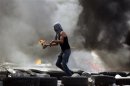 Palestinian protester gets ready to throw a Molotov cocktail during small clashes with Israeli forces following the funerals at Qalandiya Refugee Camp near Ramallah