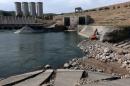 A employee operates an excavator as he works at strengthening the Mosul Dam on the Tigris River