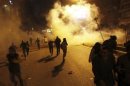Protesters flee from teargas released by riot police during clashes along a street which leads to the Muslim Brotherhood's headquarters in Cairo