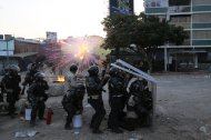 La Policía Nacional Bolivariana se protege al explotar un cohete de artificio lanzado por manifestantes antigubernamentales durante enfrentamientos en Caracas, Venezuela, el miércoles 5 de marzo de 2014. (Foto AP/Fernando Llano)