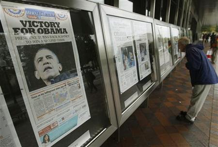 People view various newspaper front pages showing President Barack Obama's victory over Republican presidential candidate Mitt Romney on display at the Newseum in Washington November 7, 2012. REUTERS/Gary Cameron