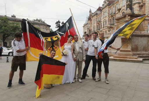 German soccer fans pose for photographs with newlyweds in central Lviv