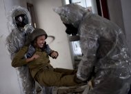 Israeli soldiers of the Home Front Command rescue unit wear protective gear during a drill in Azur, near Tel Aviv, Israel, Tuesday, May 28, 2013. Israel has launched a national civil defense drill, which the army said this year will focus on the threat of unconventional weapons at a time of growing regional tensions. (AP Photo/Ariel Schalit)