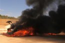 A car burns after it was set on fire by demonstrators who attacked the base of the Rafalla al-Sihati brigade, part of the Libyan army, in Benghazi city