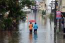 Two Indians make their way on a flooded street following heavy rain in Chennai on November 16, 2015