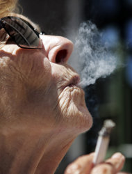 FILE - In a June 11, 2007 file photo, Helen Heinlo smokes outside of a coffee shop in Belmont, Calif. Millions of smokers could be priced out of health insurance because of tobacco penalties in President Barack Obama’s health care law, say experts. The Affordable Care Act allows health insurers to charge smokers buying an individual policy up to 50 percent higher premiums starting next Jan. 1. For a 55-year-old smoker, the penalty could reach nearly $4,250 a year. A 60-year-old could wind up paying nearly $5,100 on top of premiums. (AP Photo/Paul Sakuma, File)