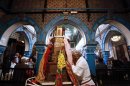 Jewish woman prays for blessings as she buries her face in the colourful scarves pinned on the Grand Menorah in the blue-tiled El Ghriba synagogue Djerba