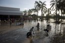 People wade through waist-high water in a store's parking, looking for valuables, south of Acapulco, in Punta Diamante, Mexico, Wednesday, Sept. 18, 2013. Mexico was hit by the one-two punch of twin storms over the weekend, and the storm that soaked Acapulco on Sunday - Manuel -re-formed into a tropical storm Wednesday, threatening to bring more flooding to the country's northern coast. With roads blocked by landslides, rockslides, floods and collapsed bridges, Acapulco was cut off from road transport. (AP Photo/Eduardo Verdugo)