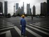 A construction worker looks at Pudong financial district as he wait to cross an avenue in Shanghai