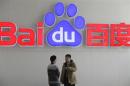 People talk in front of a Baidu's company logo at Baidu's headquarters in Beijing
