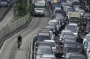 A man cycles past vehicles in a gridlocked street in Jakarta