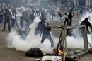 An anti-government protester throws a gas canister back at police during riots at Altamira square in Caracas