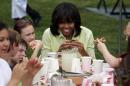 First lady Michelle Obama eats after harvesting vegetables from the summer crop from the White House Kitchen Garden in Washington