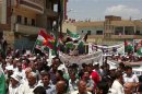 Demonstrators hold Kurdish and opposition flags during a protest against Syria's President Al-Assad in Qamishli