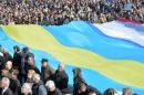 People hold a huge flag, a combination of a Ukrainian, Crimean and Tatar flags, on Independence Square in Kiev on March 23, 2014
