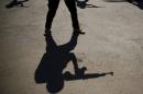 The shadows of rebel fighters carrying fake weapons are seen during a training session at a camp in Syria's rebel-held Eastern Ghouta region before being sent to the front lines, on July 11, 2015