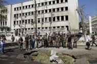 Syrian soldiers stand at the site of twin bombings near the army headquarters in Damascus. Deadly gunfire erupted around the compound following the blasts