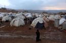 FILE - In this Monday, Nov. 18, 2013 file photo, a Syrian refugee woman walks near the tents of a refugee camp in the eastern Lebanese border town of Arsal. Inspired by the uprisings in Tunisia and Egypt, Syria's uprising began in March 2011 from the southern city of Daraa. It has since evolved into a civil war in which more than 220,000 people have been killed. (AP Photo/Bilal Hussein, File)