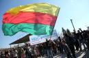 A Kurdish man waves a large flag of the Kurdish People's Protection Units (YPG) political wing, the Democratic Union Party (PYD)