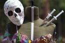 A fake skull and syringes decorate a finished outfit atop a dressmaker's dummy during a student competition to craft fashions inspired by the effects of the drug trade on Mexican culture, at the IberoAmerican University in Mexico City, Wednesday, March 16, 2016. About 200 fashion design and textile students participated in the two-hour competition, building outfits featuring skulls, fake blood and syringes. (AP Photo/Rebecca Blackwell)