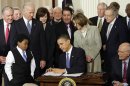 FILE - In this March 23, 2010 file photo, Marcelas Owens of Seattle, left, Rep. John Dingell, D-Mich., right, and others, look on as President Barack Obama signs the health care bill in the East Room of the White House in Washington. (AP Photo/J. Scott Applewhite, File)