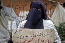An Egyptian woman holds a poster with Arabic that reads, "my Christian siblings.. happy new year.." in front of the presidential palace in Cairo, Egypt, Monday, Dec. 31, 2012. (AP Photo/Amr Nabil)