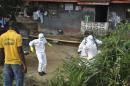 Medical staff wearing protective suits gather at a health facility near the Liberia-Sierra Leone border in western Liberia