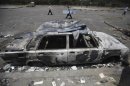 Members of Muslim Brotherhood and supporters of deposed President Mursi walk near burnt car at entrance to campsite near Tomb of the Unknown Soldier, close to Rabaa Adawiya Square, in Nasr city