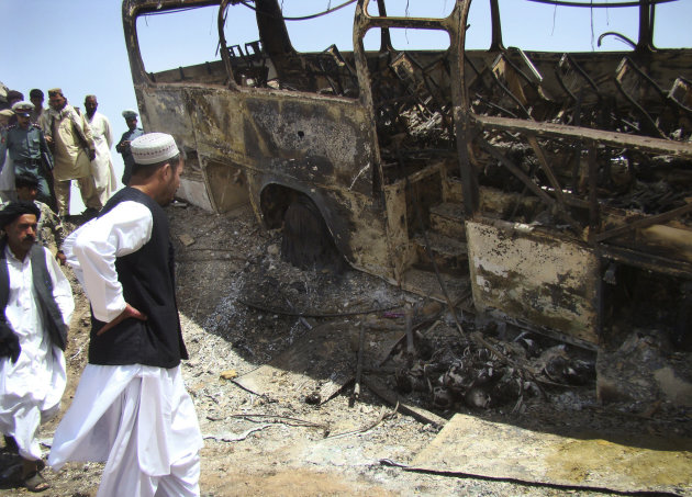 Afghan men surround a burned bus after it collided with the wreckage of a truck that was attacked by Taliban insurgents in Maiwand district, on the highway between Kandahar and Helmand, Afghanistan, Friday, April 26, 2013. Scores of people aboard the bus were killed in the fiery crash, officials said. (AP Photo/Abdul Khaliq Kandahari)