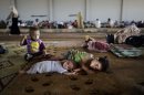 Syrian children, who fled their home with their family due to fighting between the Syrian army and the rebels, lie on the ground, while they and others take refuge at the Bab Al-Salameh border crossing, in hopes of entering one of the refugee camps in Turkey, near the Syrian town of Azaz, Sunday, Aug. 26, 2012. Thousands of Syrians who have been displaced by the country's civil are struggling to find safe shelter while shelling and airstrikes by government forces continue. (AP Photo/Muhammed Muheisen)