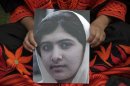 A student holds an image of Malala Yousufzai, who was shot on Tuesday by the Taliban, during a rally in Lahore