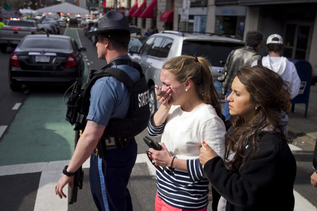 A woman who apparently sustained an injury to her hand, walks with another who tries to comfort her after explosions reportedly interrupted the running of the 117th Boston Marathon in Boston