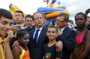 FILE - In this Wednesday, July 31, 2013 file photo, French President Francois Hollande, center, poses with residents during his visit to 'Clichy Sand' in Clichy-sous-Bois, outside Paris. Two weeks after a spurt of rioting in a far-flung Paris suburb, Hollande is injecting a new dose of funds to help cure one of France's most persistent problems, the suburban housing projects with their volatile mix of joblessness, high immigration, crime and despair. (AP Photo/Jacques Brinon, Pool, File)
