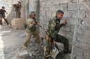 A Kurdish gunman uses a hammer to open a hole in a wall near Shi'ite militiamen positions during clashes Tuz Khurmato