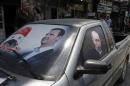 Election poster of Syria's President Bashar al-Assad and a photo of Russian President Vladimir Putin are seen on a car at al-Qardahah town