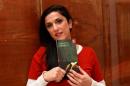 Israeli author Dorit Rabinyan posing with her Hebrew-language novel titled "Gader Haya"