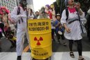 An anti-nuclear protester wearing a gas mask beats a mock nuclear waste container during a demonstration near Tokyo Electric Power Co headquarters building in Tokyo