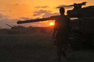 An Israeli soldier walks past a Merkava tank along &hellip;