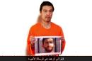 Image obtained from a video uploaded to YouTube on January 27, 2015 shows a still image of Japanese hostage Kenji Goto holding a photo allegedly showing captured Jordanian pilot Maaz al-Kassasbeh