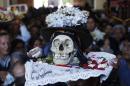 A man carries a decorated human skull or "natita" inside the Cementerio General chapel during the Natitas Festival celebrations in La Paz, Bolivia, Friday, Nov. 8, 2013. The Roman Catholic church considers the skull festival to be pagan, but it doesn't prohibit people from participating in it. Mass was not being held at the chapel on Friday, but a bowl of holy water was left out so people could bless the skulls they were carrying in the ritual celebrated a week after Day of the Dead. (AP Photo/Juan Karita)