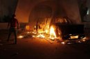 Demonstrator stands next to a burning car after protesters stormed the headquarters of the Islamist Ansar al-Sharia militia group in Benghazi