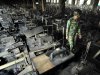 FILE - In this Sunday, Nov. 25, 2012 file photo, a Bangladeshi police officer walks past rows of burnt sewing machines in the burned out Tazreen garment factory in Savar, on the outskirts of Dhaka, Bangladesh. Government investigators said the November fire at the Tazreen factory, which killed 112, was so deadly in part because clothing was stored in the stairwell, which turned the emergency exit into a chimney billowing smoke, fire and toxic fumes from the burning fibers. (AP Photo/Khurshed Rinku, File)