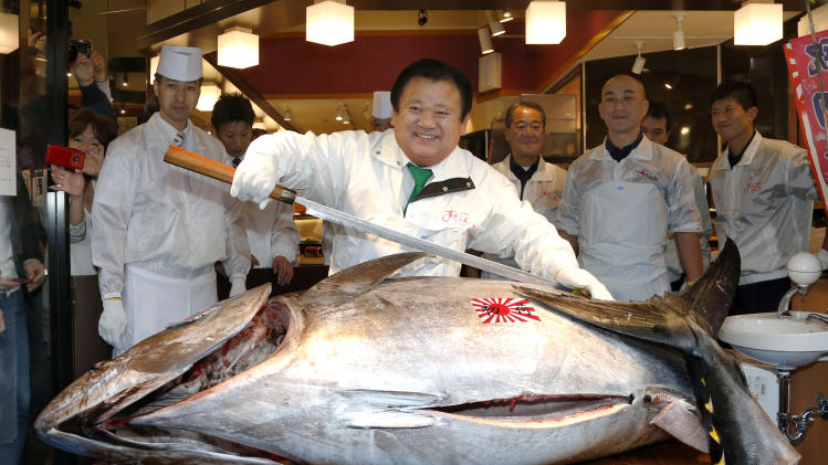 Sushi restauranteur Kiyoshi Kimura poses with a 507-pound (230-kilogram) bluefin tuna he bought at an auction before cutting it at his restaurant near Tsukiji fish market in Tokyo, Sunday, Jan. 5, 2014. Kimura paid 7.36 million yen (about $70,000) for the bluefin tuna in the year's celebratory first auction, just one-twentieth of what he paid a year earlier despite signs the species is in serious decline. (AP Photo/Shizuo Kambayashi)