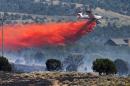A small air tanker drops retardant on a fire burning in Stockton Utah Wednesday, July 16, 2014. Officials say a wildfire encroaching on homes in the Tooele County town of Stockton has overtaken 400-500 acres. Utah Division of Forestry, Fire and State Lands spokesman Jason Curry says he believes no homes have been destroyed. (AP Photo/The Salt Lake Tribune, Scott G Winterton)