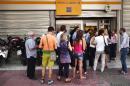People queue at ATM machines outside a branch of Piraeus Bank in central Athens on June 29, 2015