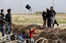 Syrians throw their belongings while trying to cross a ditch after crossing from the northern Syrian town of Ras al-Ain to Turkey in the border town of Ceylanpinar, Sanliurfa province